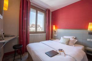 a hotel room with a bed with a book on it at Contact Hôtel Le Relais de Vellinus in Beaulieu-sur-Dordogne