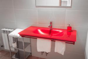 um lavatório vermelho na casa de banho com toalhas brancas em Hotel Rural Casa La Era em Galve