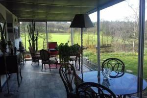 a patio with a table and chairs and a large window at Angelina et ses animaux in Pléchâtel