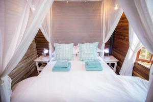 a bedroom with a white bed with blue pillows at Paradise Dunes in Praia do Tofo