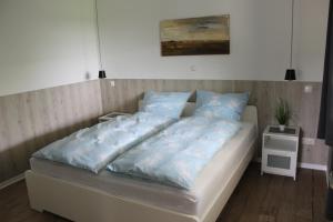 a bed with blue pillows on it in a room at Haus Kornblume in Oberlangen