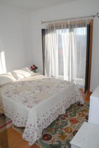 a bedroom with a bed with a floral bedspread and a window at Casa de Penedones in Penedones