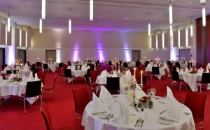 a banquet hall with white tables and red chairs at The Monarch Hotel in Bad Gögging +29 photos