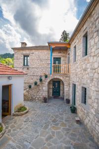 a stone building with a green door and a balcony at Hotel Arhontiko Vourloka in Pramanta