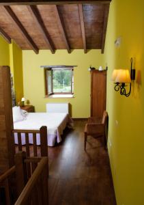 a bedroom with yellow walls and a bed and a window at O Plantio in Porto de Espasante
