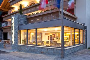 un bâtiment avec des fenêtres et des drapeaux devant lui dans l'établissement Hotel Alpenblick, à Sarentino