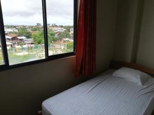 a bedroom with a bed and two windows with a view at Hospedaje el Emperador in Pucallpa