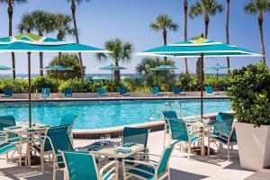a restaurant with tables and umbrellas next to a swimming pool at Resort at Longboat Key Club in Sarasota
