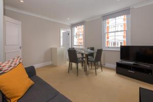 a living room with a couch and a table with chairs at One bedroom High street kensington Apartment in London
