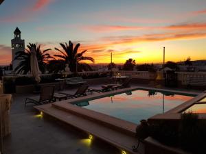 a pool on top of a building with a sunset at Maison d'Hôtes Dar Ennassim in La Marsa