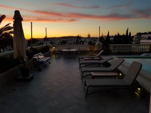 a rooftop patio with couches and tables and a sunset at Maison d'Hôtes Dar Ennassim in La Marsa