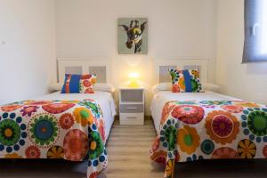 a bedroom with two beds with colorful sheets at Hostal Los Gabrieles in Albacete