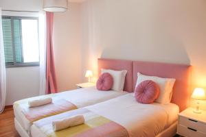 フンシャルにあるThe Seaside Apartmentのベッドルーム1室(ピンクの枕が付いた大型ベッド1台付)