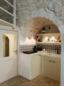 a kitchen with white cabinets and a stone wall at Solis Domus - Meridies in Ostuni
