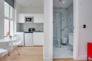 cocina con armarios blancos y ducha acristalada en Chapel Market Serviced Apartments by Concept Apartments, en Londres
