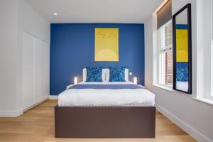 Un dormitorio con una pared azul y una cama en Chapel Market Serviced Apartments by Concept Apartments, en Londres
