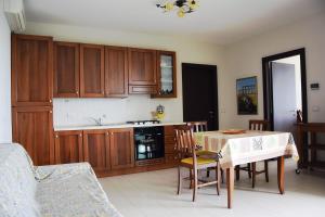una cocina con armarios de madera y una mesa con sillas. en Appartamento Malvarosa en Colonnella