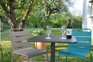 una mesa y 2 sillas con una botella y una copa de vino en L'Atelier, en Sainte-Marie-du-Lac-Nuisement 