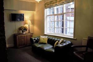 a living room with a leather couch and a window at White Horse & Griffin in Whitby