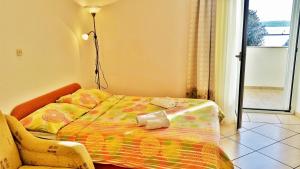 a bedroom with a bed and a lamp and a chair at Obala Apartment & Studios in Malinska