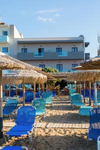 eine Gruppe blauer Stühle und Sonnenschirme am Strand in der Unterkunft Tropical Beach A in Ammoudara