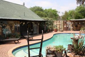 a swimming pool with chairs and plants in a yard at The Yardt Guest House in Trichardt