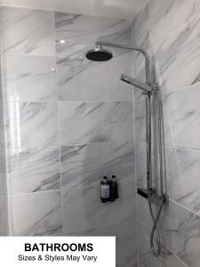 La salle de bains est pourvue d'une douche et de carrelage en marbre blanc. dans l'établissement Seafront419 By Seafront Collection, à Blackpool