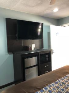 a room with a tv and a desk with a microwave at Star Light Inn in Channelview
