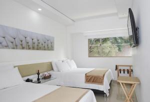 1 dormitorio blanco con 2 camas y ventana en Hotel Zona A, en Medellín
