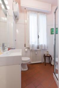 a white bathroom with a toilet and a sink at Roommo Savonarola in Florence