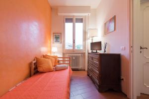 a bedroom with a bed and a dresser with a television at Roommo Savonarola in Florence
