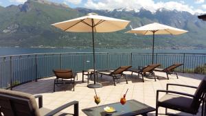 eine Terrasse mit Tischen, Stühlen und Sonnenschirmen in der Unterkunft Hotel Mercedes in Limone sul Garda