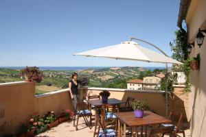 a woman standing on a balcony with an umbrella at B&B Le Terrazze Fermo in Fermo