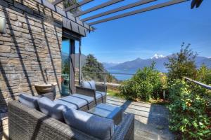 a patio with wicker furniture and a view of the water at Sant’Andrea Penthouse in Menaggio