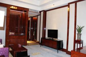 a living room with a tv on a wall at Tai Zhou International Jinling Hotel in Taizhou