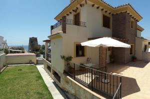 een huis met een balkon met een paraplu bij Precioso chalet con mar a 50 metros. in Chilches