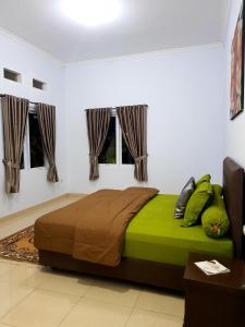 a bedroom with a bed with green sheets and windows at Villa Jidah in Gegarbensang