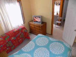 um quarto com uma cama e uma televisão numa cómoda em Alojamiento económico a pasos del Jumbo! em La Serena