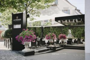 ein Restaurant mit Tischen, Stühlen und Blumen in der Unterkunft Gutwinski Hotel in Feldkirch