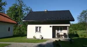 una pequeña casa blanca con techo negro en Karolówka en Horyniec