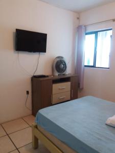 1 dormitorio con 1 cama y TV de pantalla plana en casa na praia, en Porto Belo