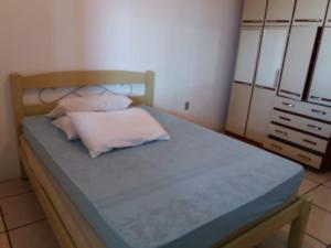 Dormitorio pequeño con cama con sábanas y almohadas azules en casa na praia, en Porto Belo