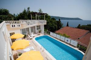 ein Haus mit Swimmingpool und Sonnenschirmen in der Unterkunft Villa Tenžera in Herceg-Novi