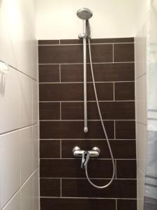 a shower with a hose in a tiled bathroom at feelgood Apartments - Apartment Chic in Braunschweig