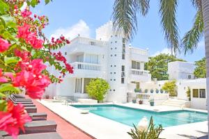a large white building with a swimming pool and pink flowers at Le Castel Blanc Hotel Boutique in San Andrés
