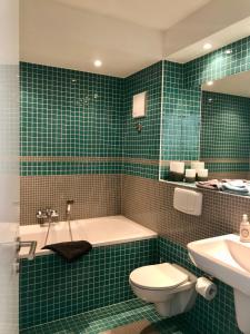 uma casa de banho com azulejos verdes, uma banheira e um WC. em Mini-Reihenhaus "Alte Buchdruckerei" em Heringsdorf
