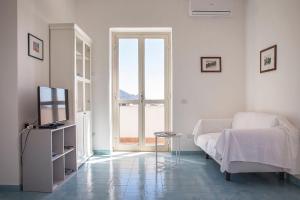 Cette chambre blanche comprend un lit et une télévision. dans l'établissement Dolce Vista Apartment Amalfi Coast, à Scala