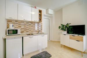 een keuken met witte kasten en een magnetron bij Studio apartments Kalma in Dubrovnik