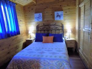 a bedroom with a bed with blue and orange pillows at CABAÑAS DE MADERA LA FLORIDA in Arroyo Frio