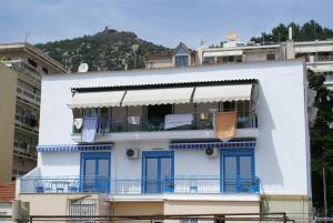 a white building with blue windows and a balcony at Island Apartment in Kavála